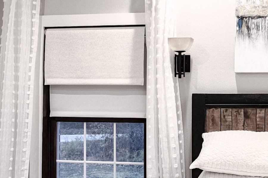 White motorized roller shade on a bedroom window